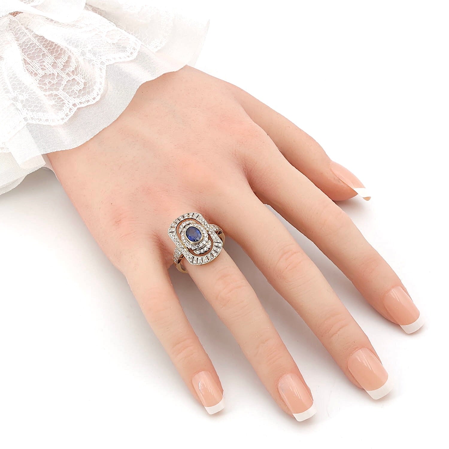 Art-Déco Ring in 750er Gold mit einem blauen Saphir und Brillanten, an einer künstlichen Hand