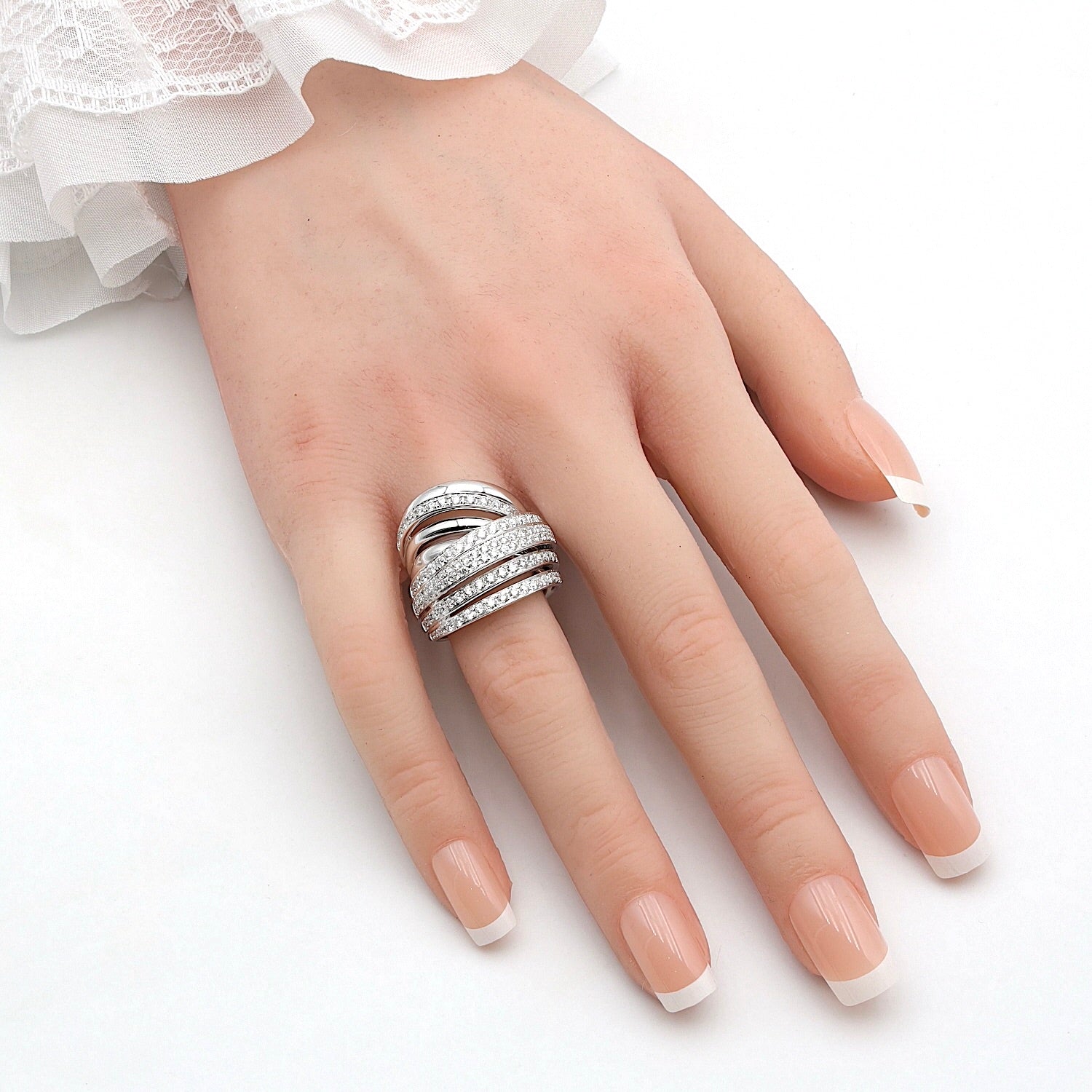 K di Kuore Cross over Ring in 750er Weißgold mit insgesamt ca. 1,15 ct Brillanten, an einer künstlichen Hand  Cross over zur Fingerspitze zeigend